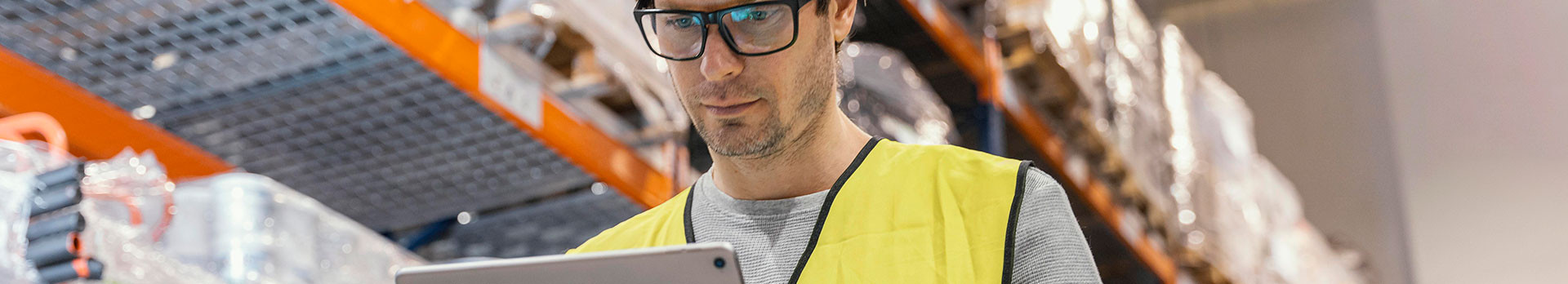 A képen egy férfi néz egy tabletet egy raktárépületben